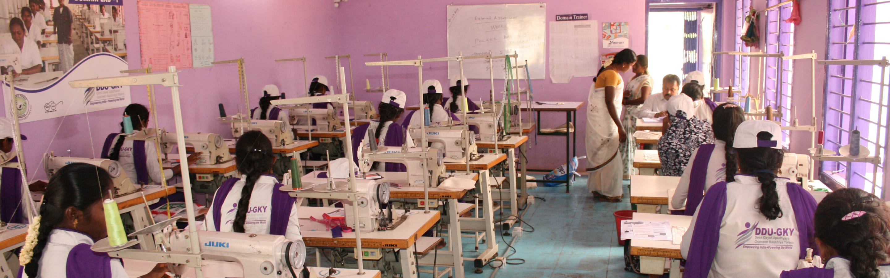 Trainees at industrial sewing machines in a DDU-GKY vocational tailoring hall