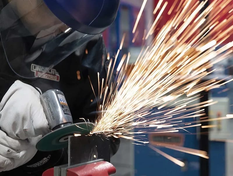 A welding student makes a cut on a piece of metal in a UTI lab.