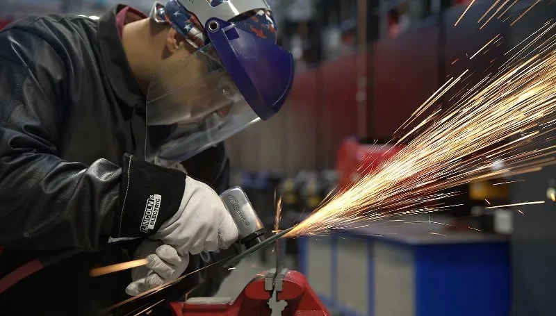 A welding student makes a cut on a piece of metal in a UTI lab.