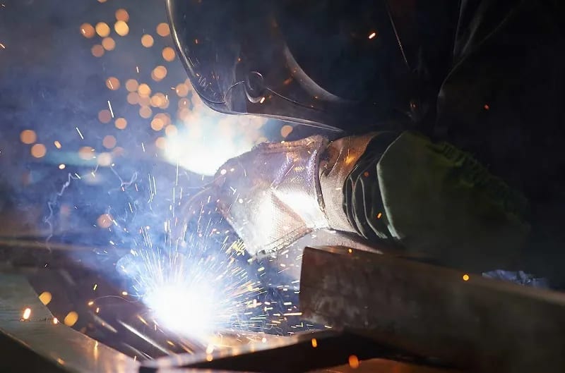 A welder works on a sheet of metal.