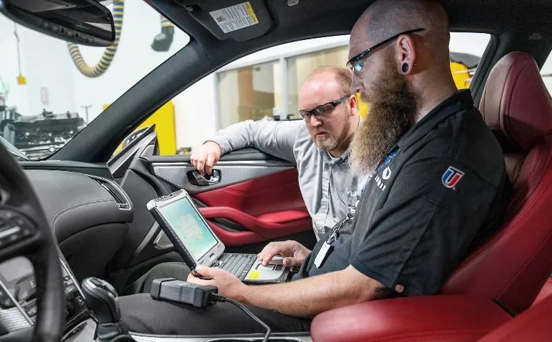 An Automotive instructor helps a student in a UTI lab.