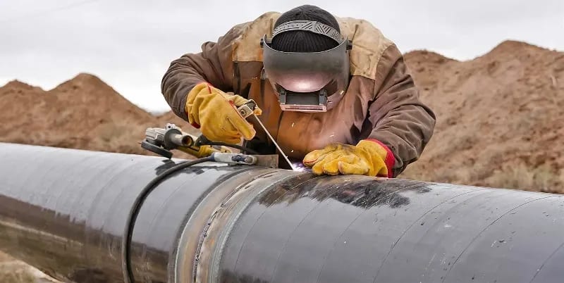 A welder repairs a pipeline.