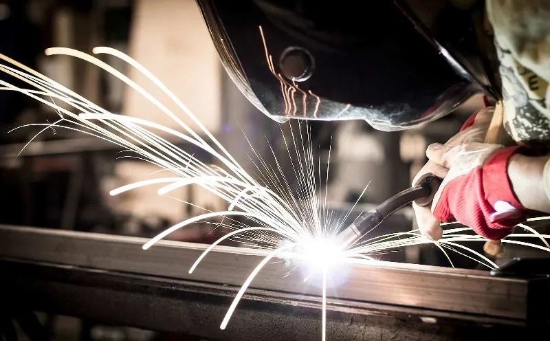 A welder makes a cut on a piece of metal.