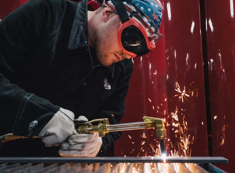 A welder makes a cut on a piece of metal.