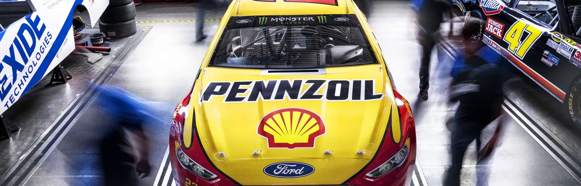 An image of a NASCAR car sponsored by Pennzoil being worked on by NASCAR Tech and Universal Technical Institute graduates