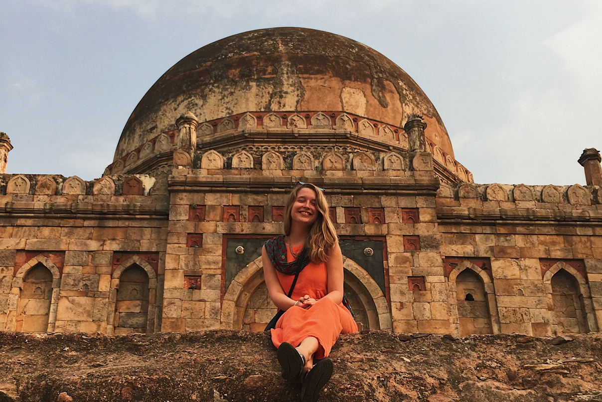 Student sitting on a wall in front of a stone temple
