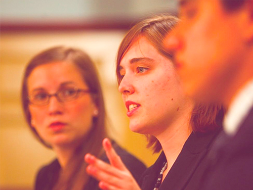 Two women and one man dressed in suits speaking to an audience