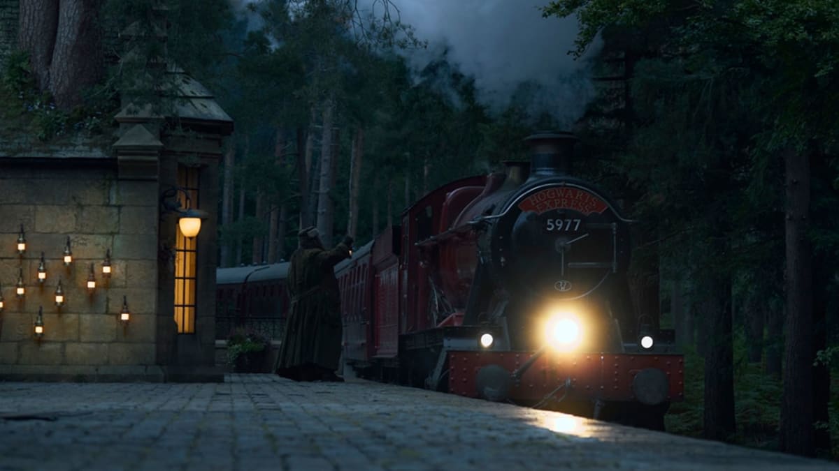 The Hogwarts Express steam train arriving at a lamplit station at night in HBO's Harry Potter series