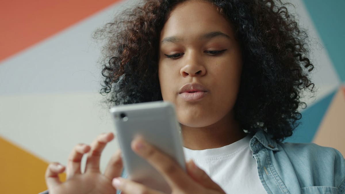 Teenager scrolling on a smartphone, illustrating the NZ social media ban for under-16s
