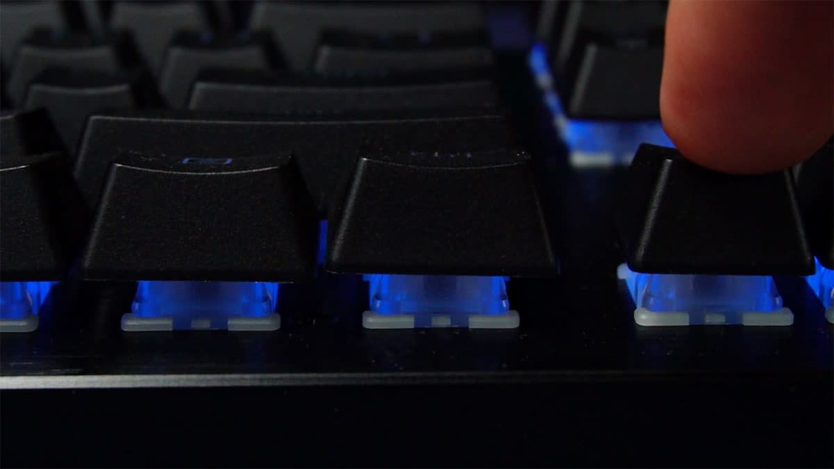 Close up of a finger pressing a key on the Razer Huntsman V3 HE Magnetic TKL, with backlighting visible beneath the keycaps.