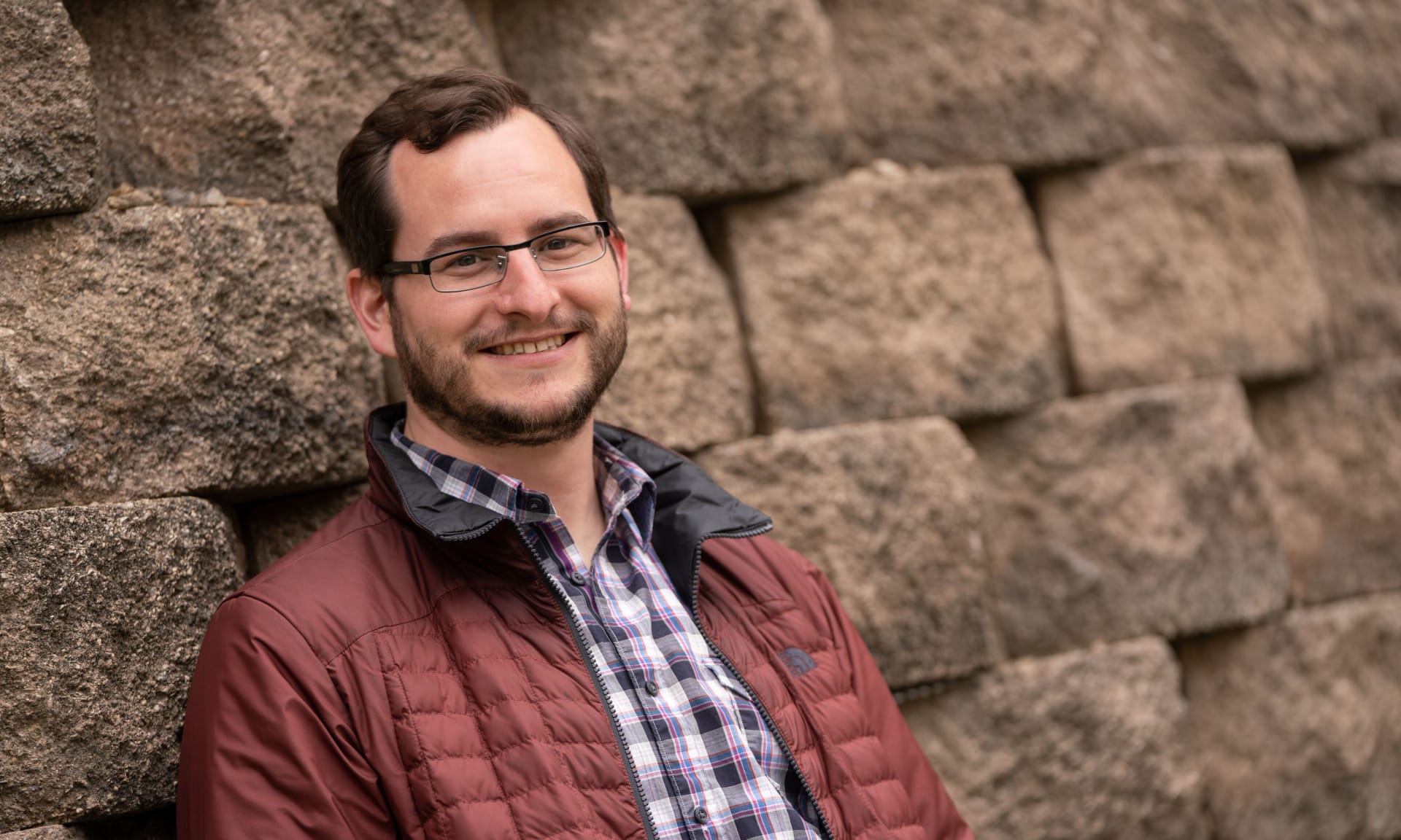 Living Donor 247712-2439.jpg A smiling man leaning against a stone wall