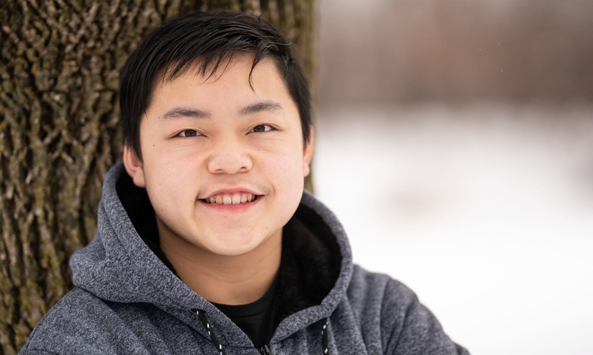Andy Thor 468245-3737.jpg A smiling teenage boy standing next to a tree