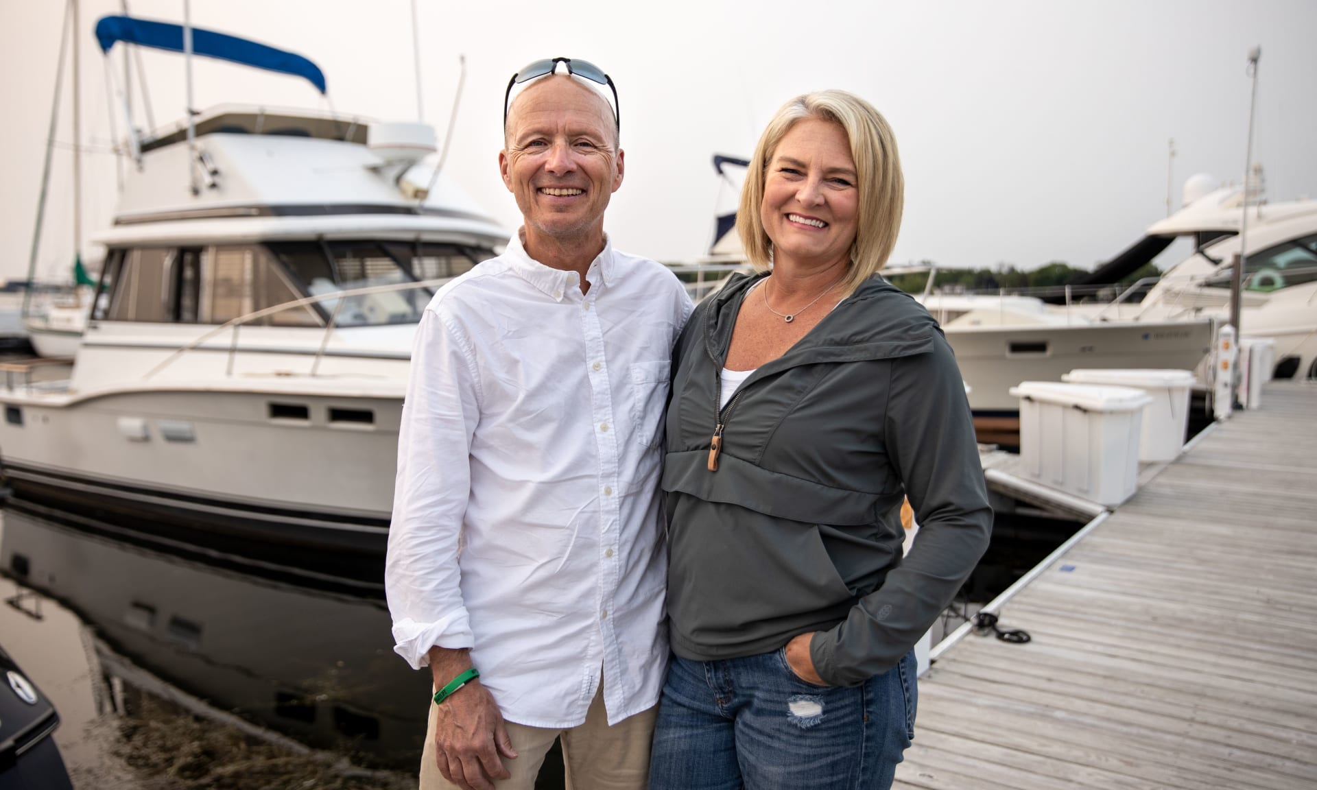 Scott Bader 372485-0737.jpg A smiling husband and wife standing on a pier in front of a boat