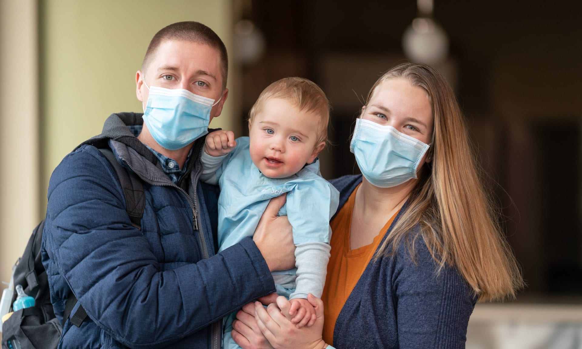 619046 Calvin-2860 man and woman wearing face masks holding a child