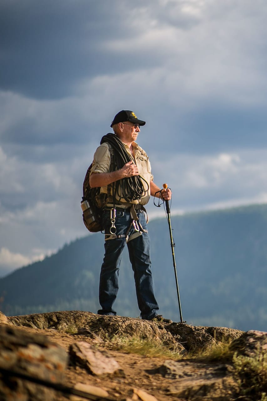 Eckert 210301-1001.jpg Man in hiking gear standing on top of a mountain peak.