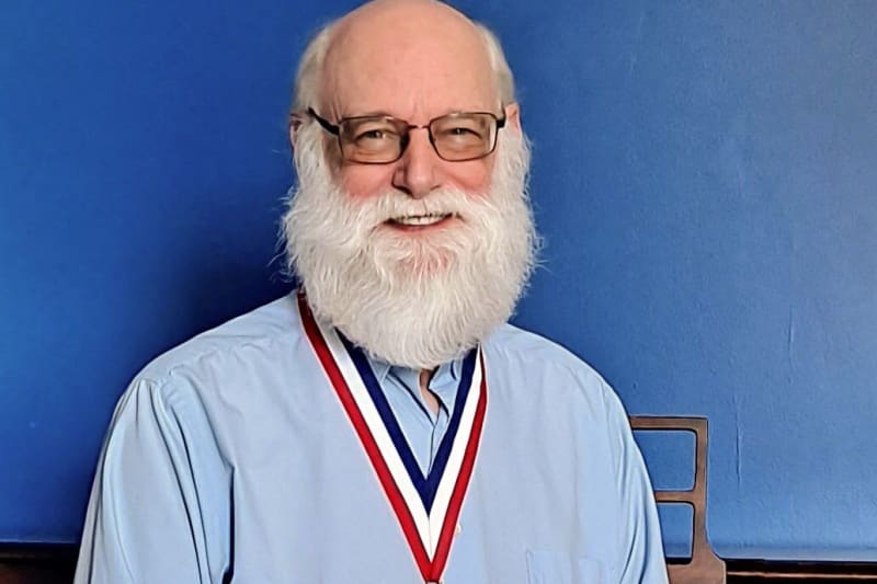 John Nelson smiling, wearing a medal