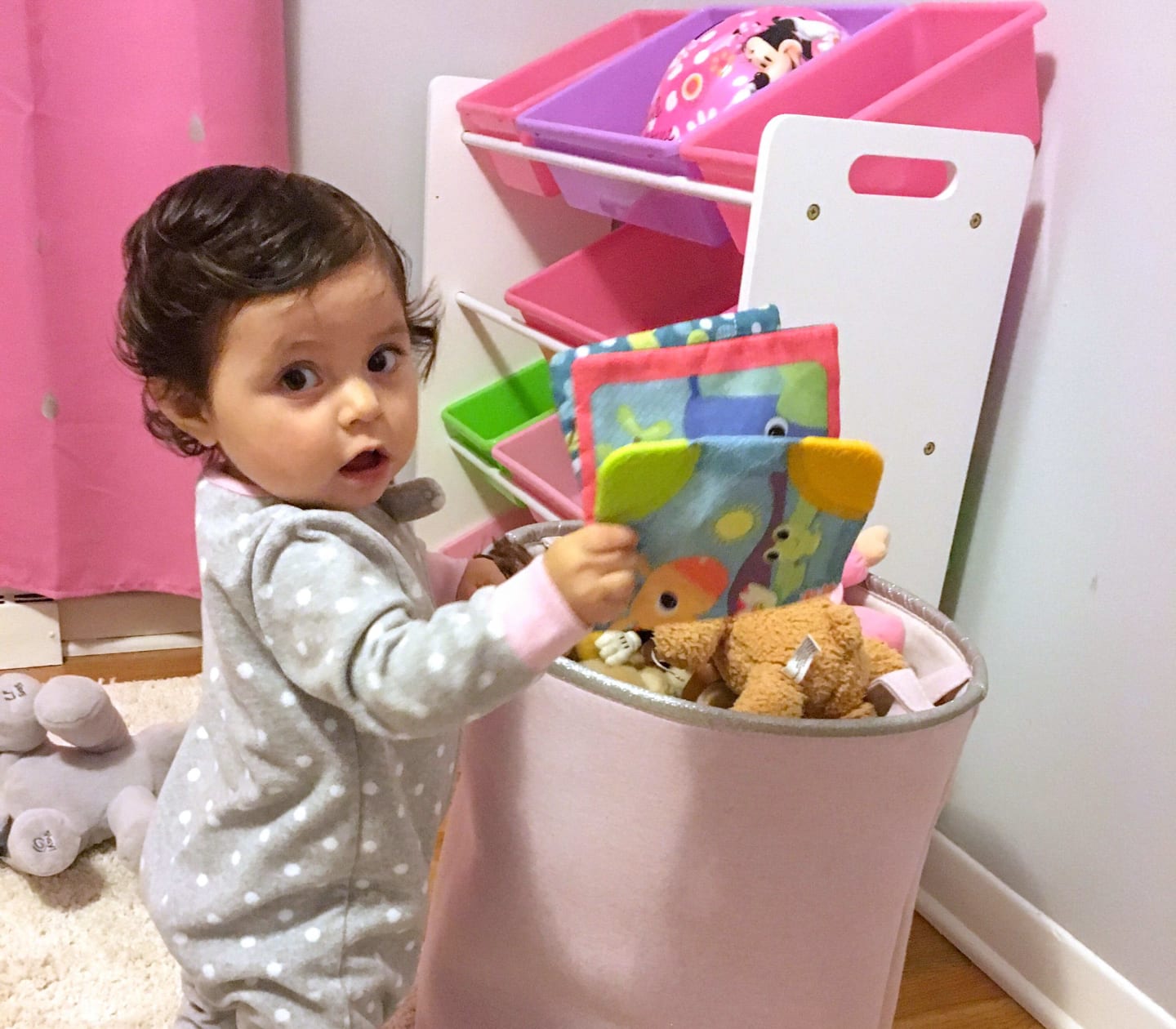 Milena Leon, a baby, standing in front of a basket of toys