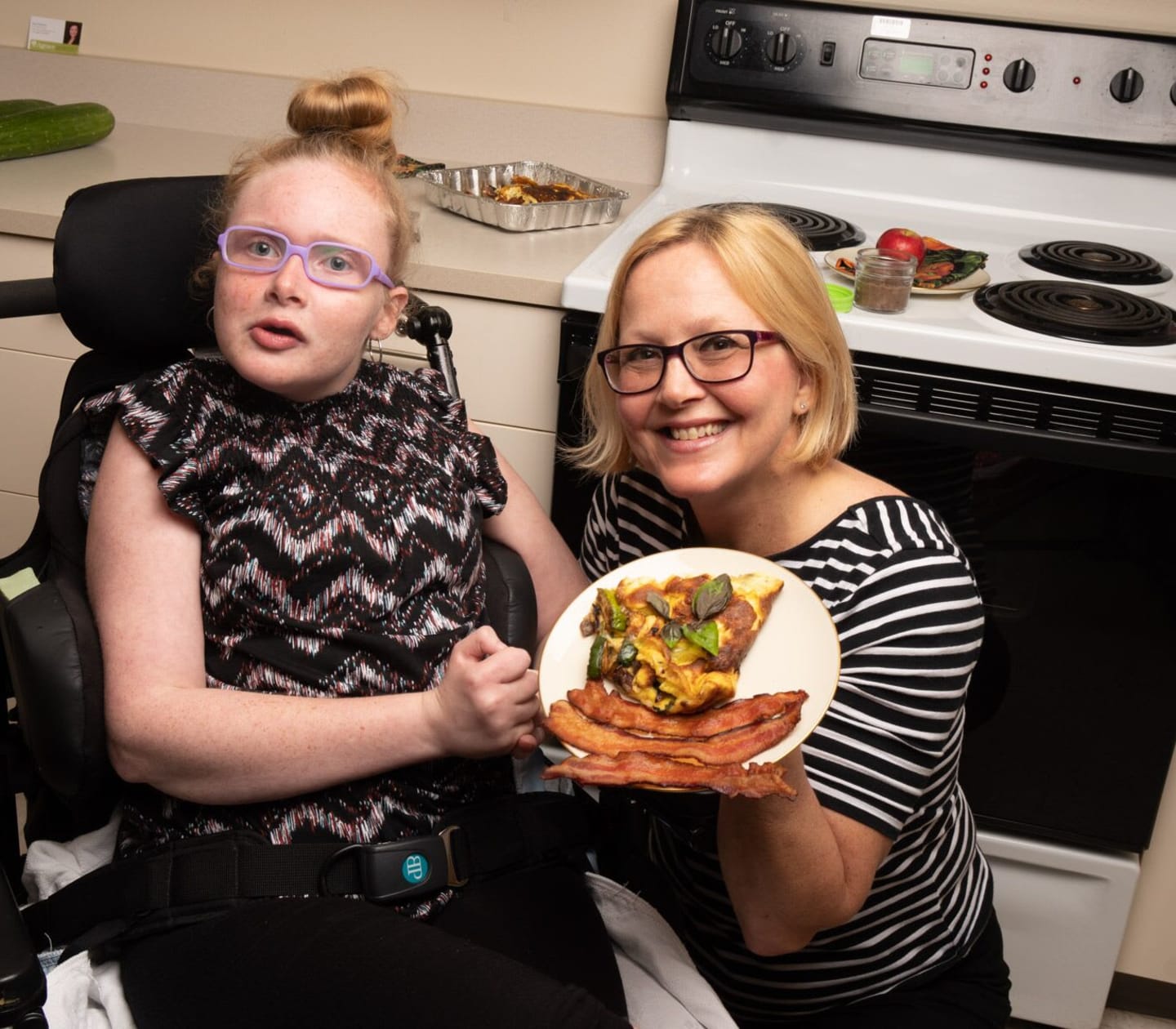 Young girl with mom in the kitchen showing off a plate of food