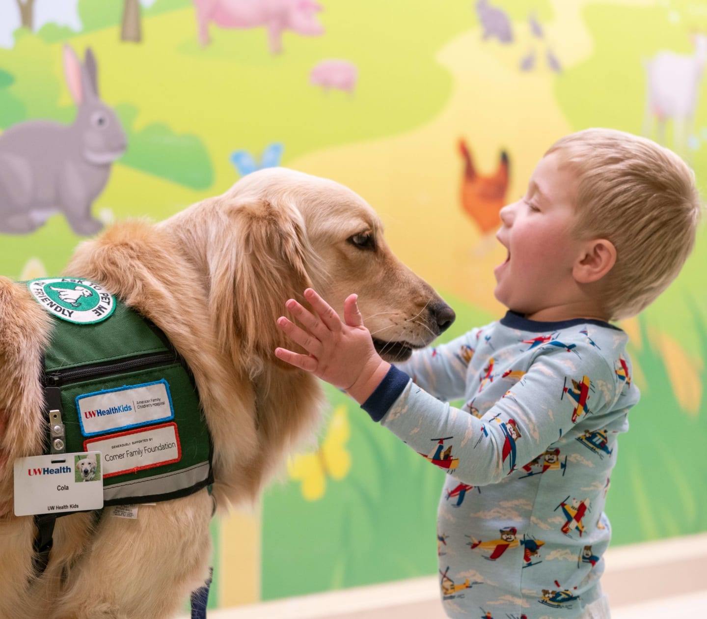 Calvin, a young boy, smiling while petting a Golden Retriever at American Family Children's Hospital.