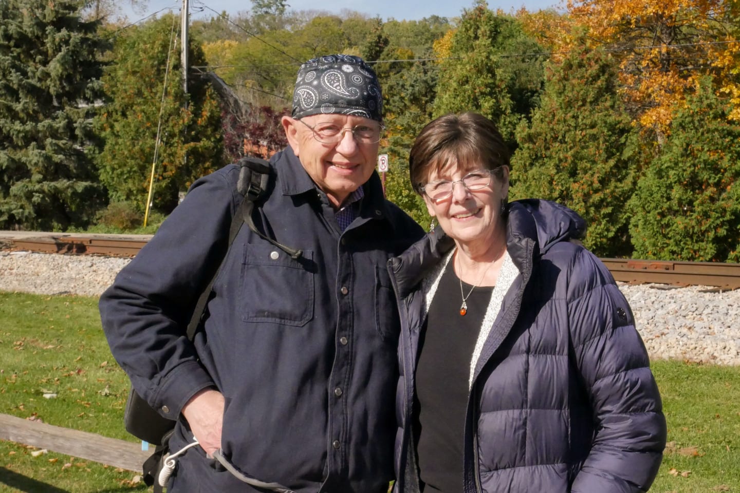 Daniel Ferguson and his wife Rene standing in front of railroad tracks on a fall day