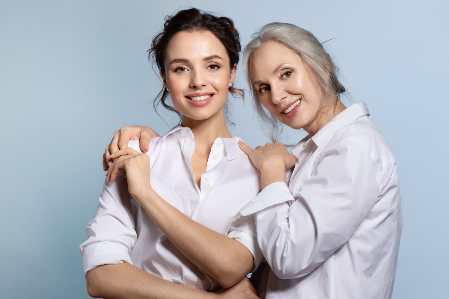 A mother and adult daughter smiling, leaning on each other