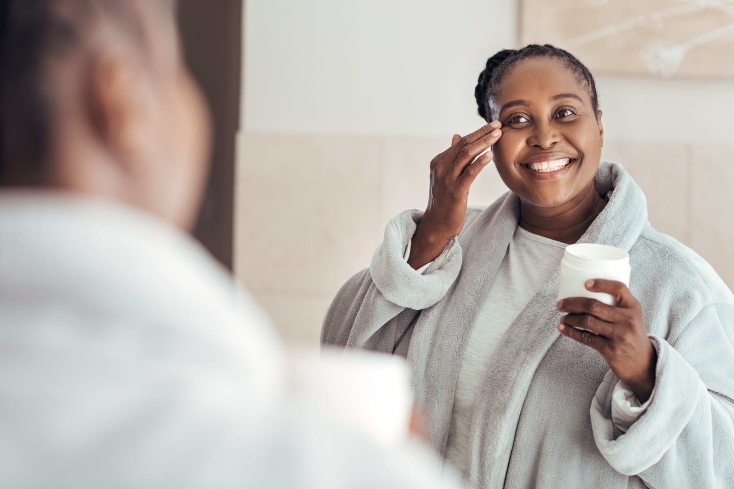 Woman applying face cream in mirror