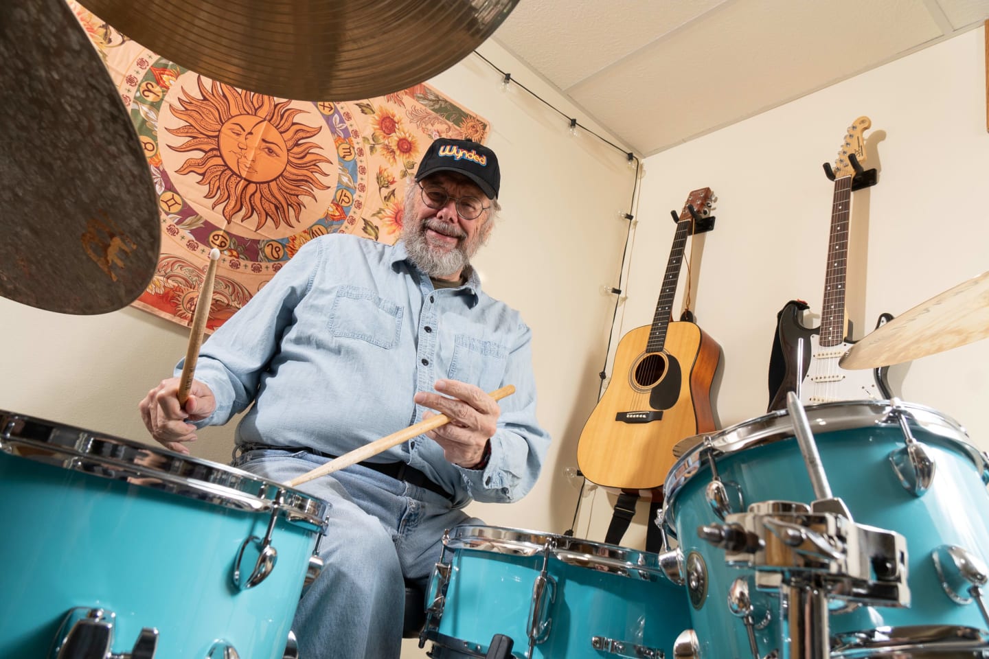 Cliffe Connor wearing a cap and playing a drumset.