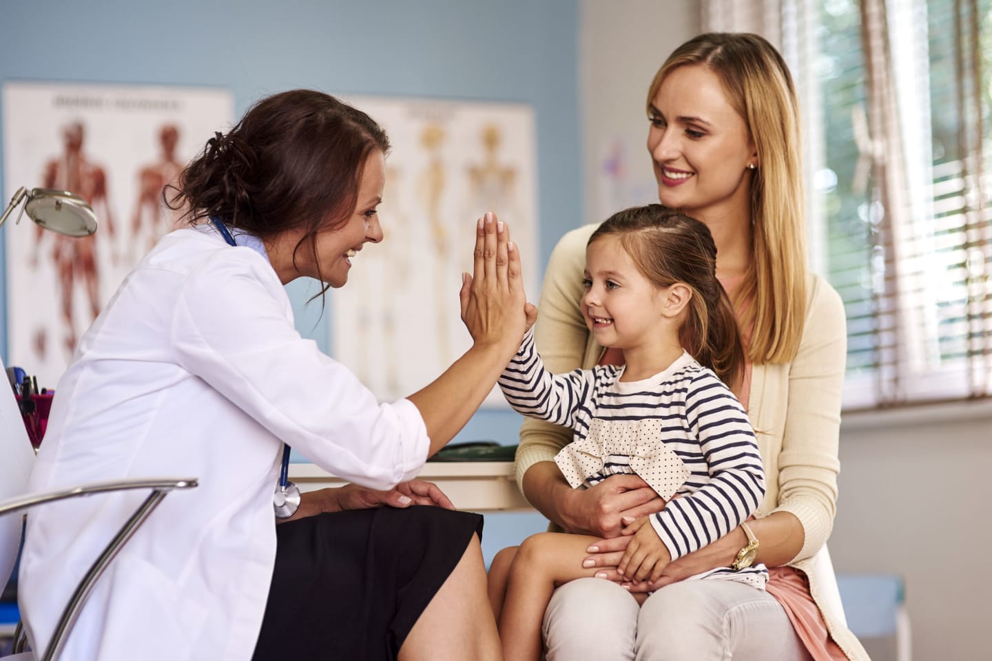 Female physician giving young girl a high-5 during a doctor's appointment