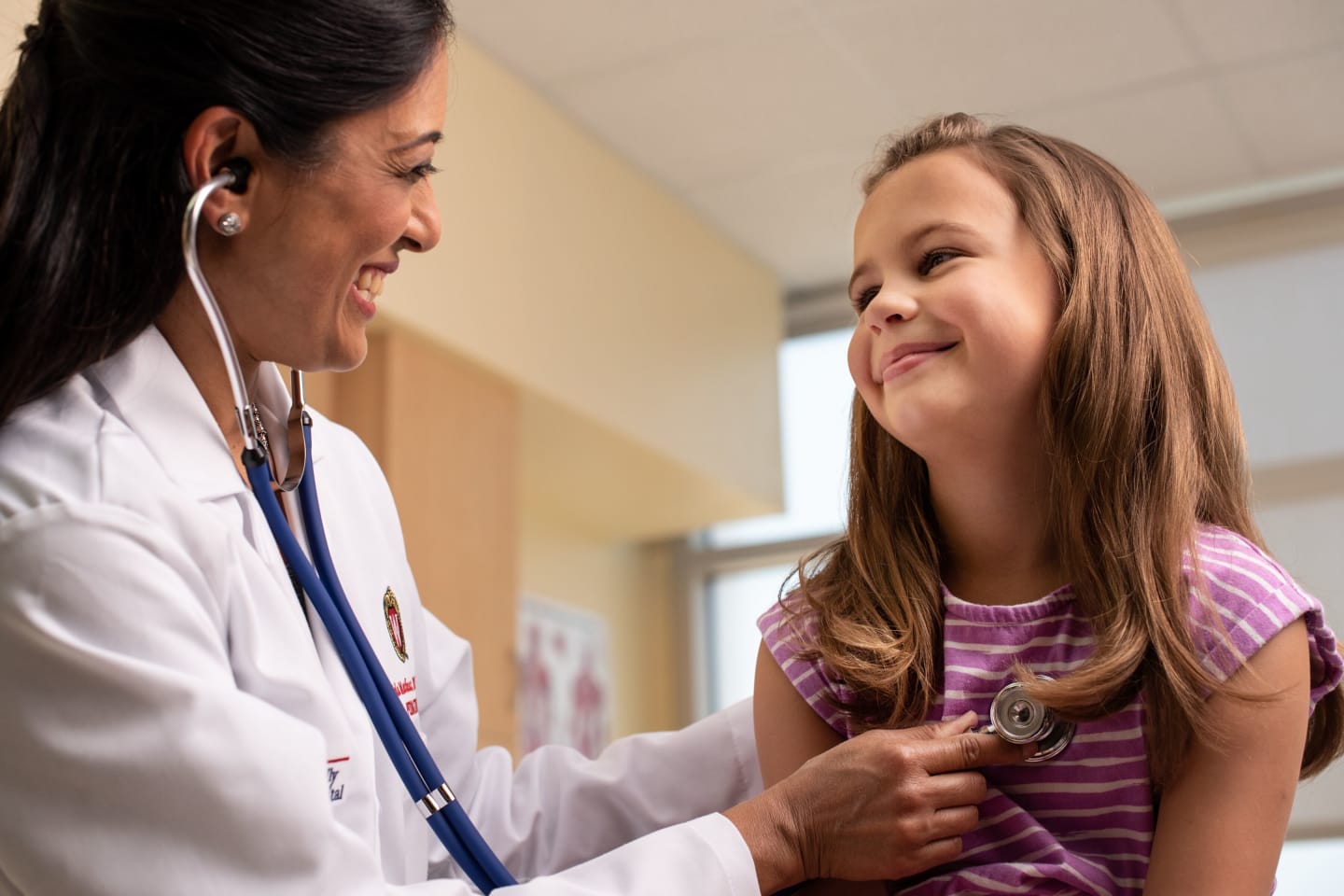 A doctor using a stethoscope to listen to a young girl's heart