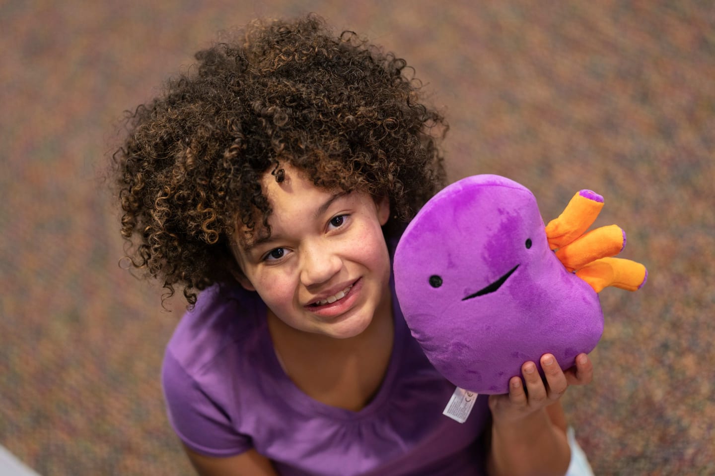 Lyla Cola smiling and holding a stuffed plush kidney toy.