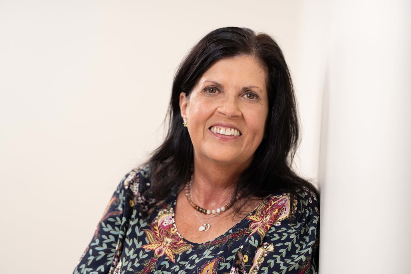 Woman leaning against wall and smiling.