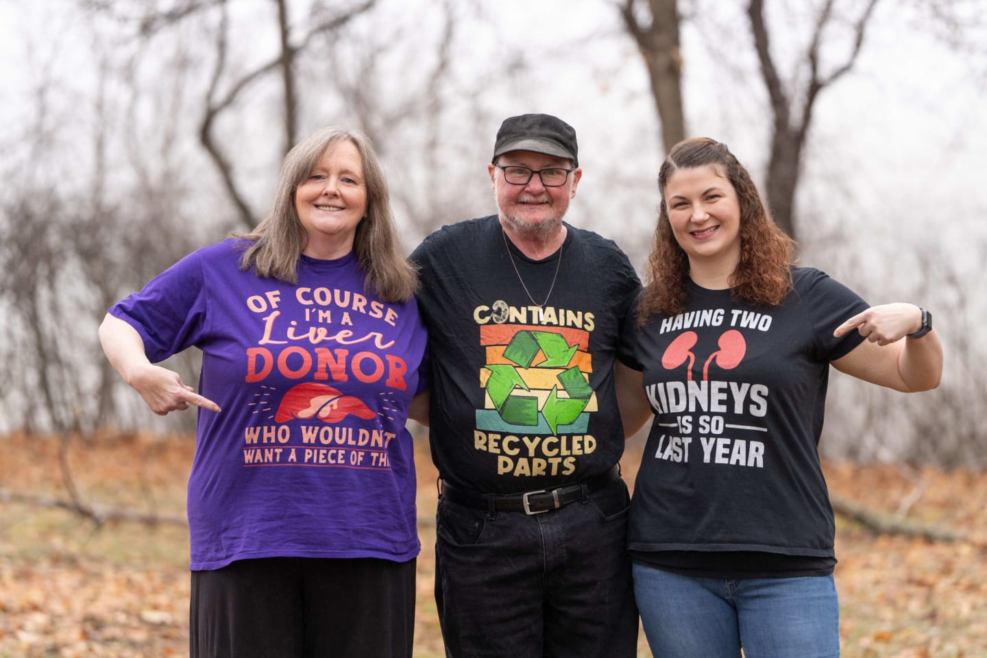 The two women standing on either side of a man, smiling. The woman on the left donated her liver, and on the right donated her kidney.