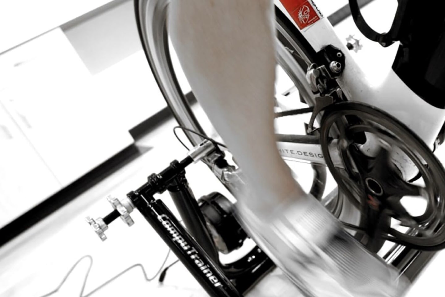 A closeup of a cyclist's leg spinning on an indoor trainer