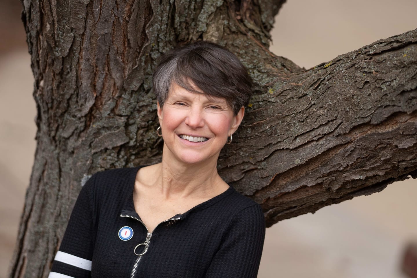 Woman leaning against a tree and smiling.