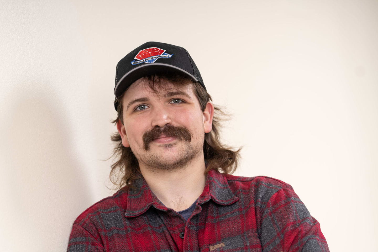 Man with a mustache and a black baseball cap, smiling.