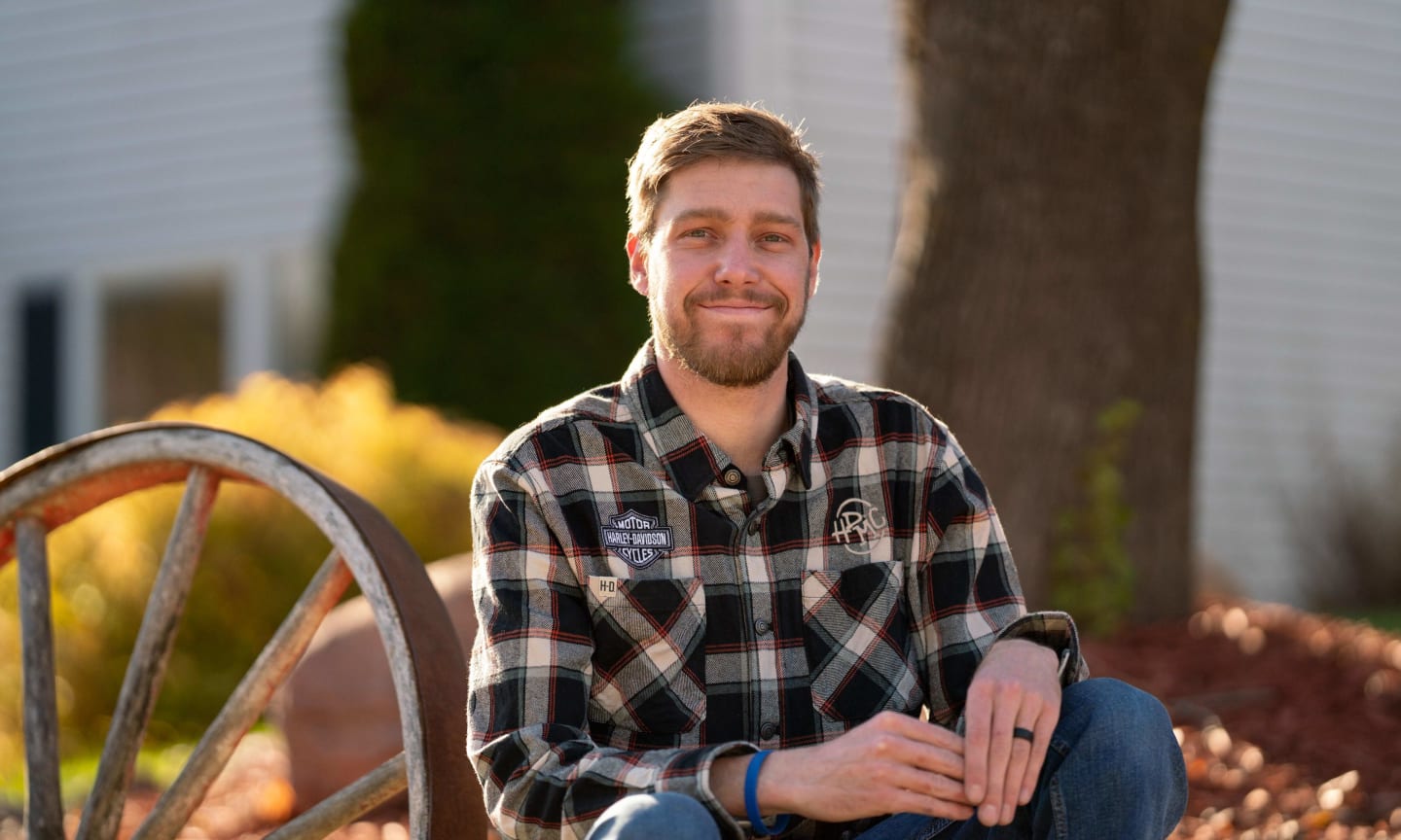 Paul Langenecker crouching next to a wagon wheel