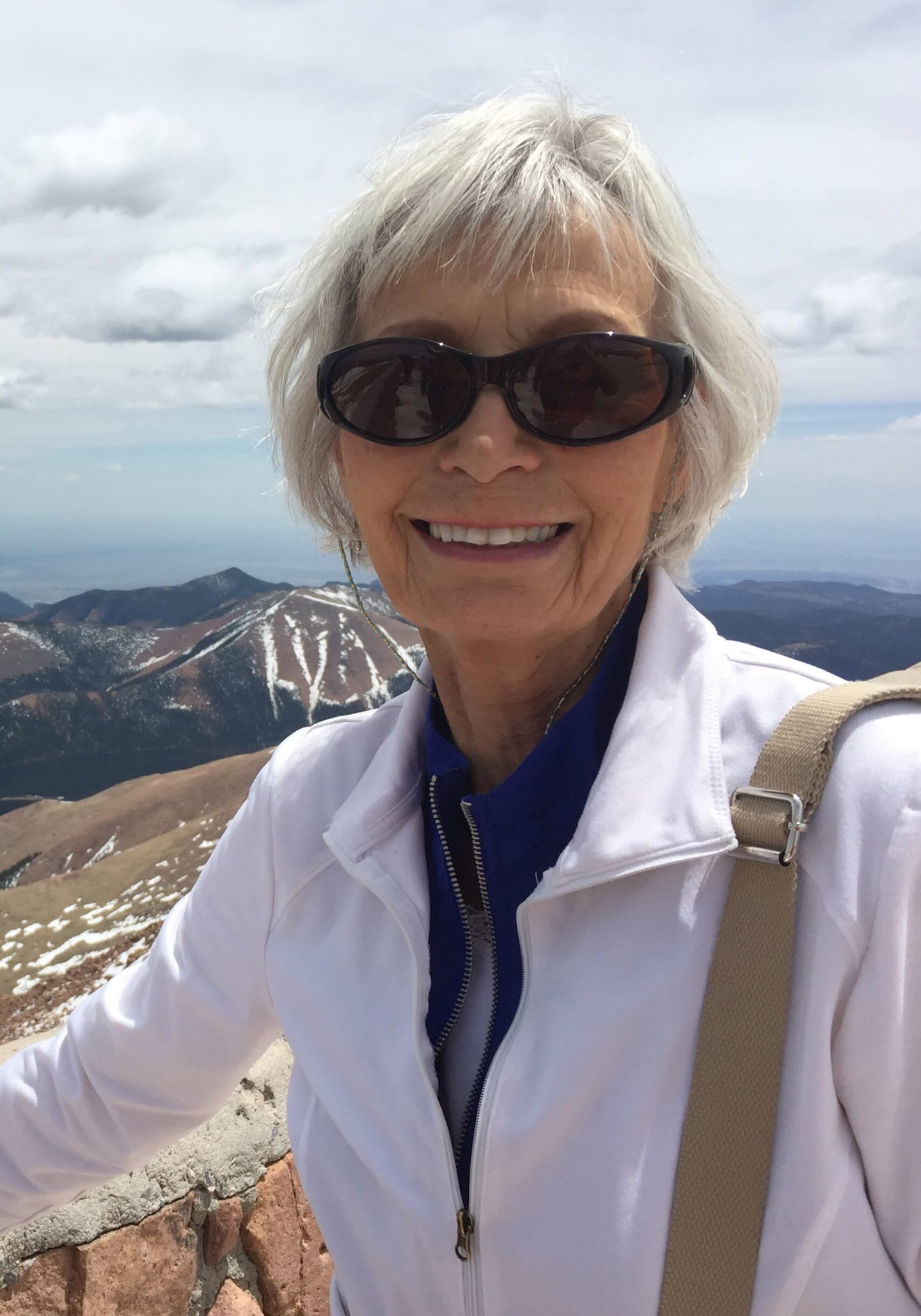 Dorothy Perpich standing at a scenic overlook with mountains in the background