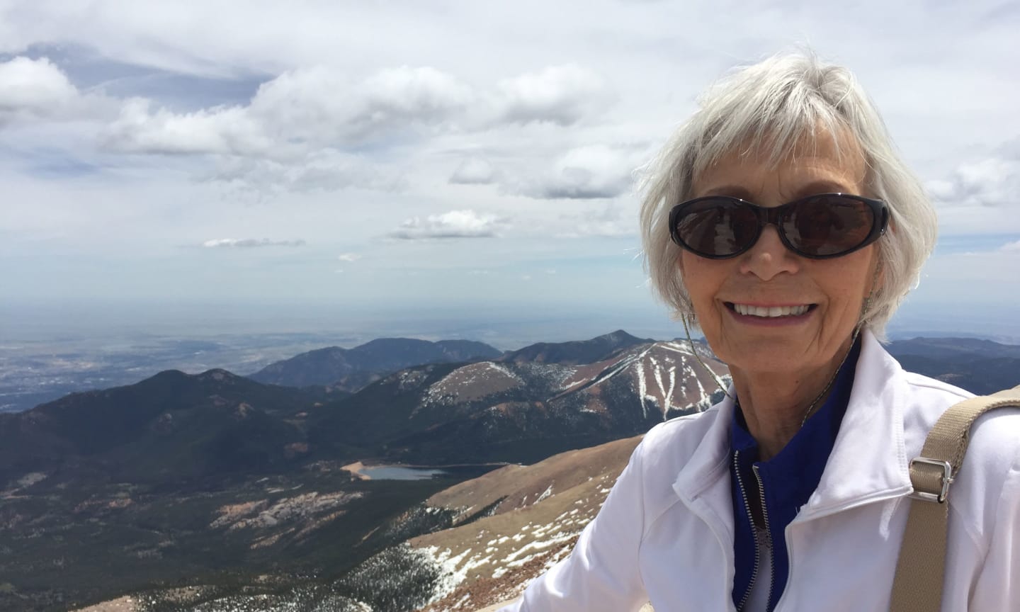 Dorothy Perpich standing at a scenic overlook with mountains in the background