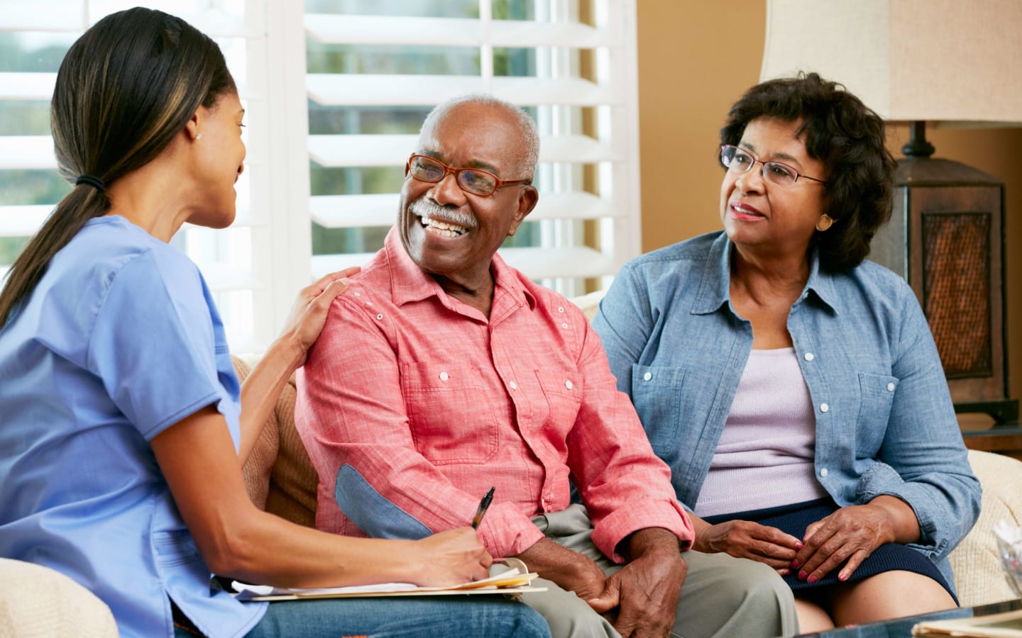 A couple talking to an in-home health care worker in their living room