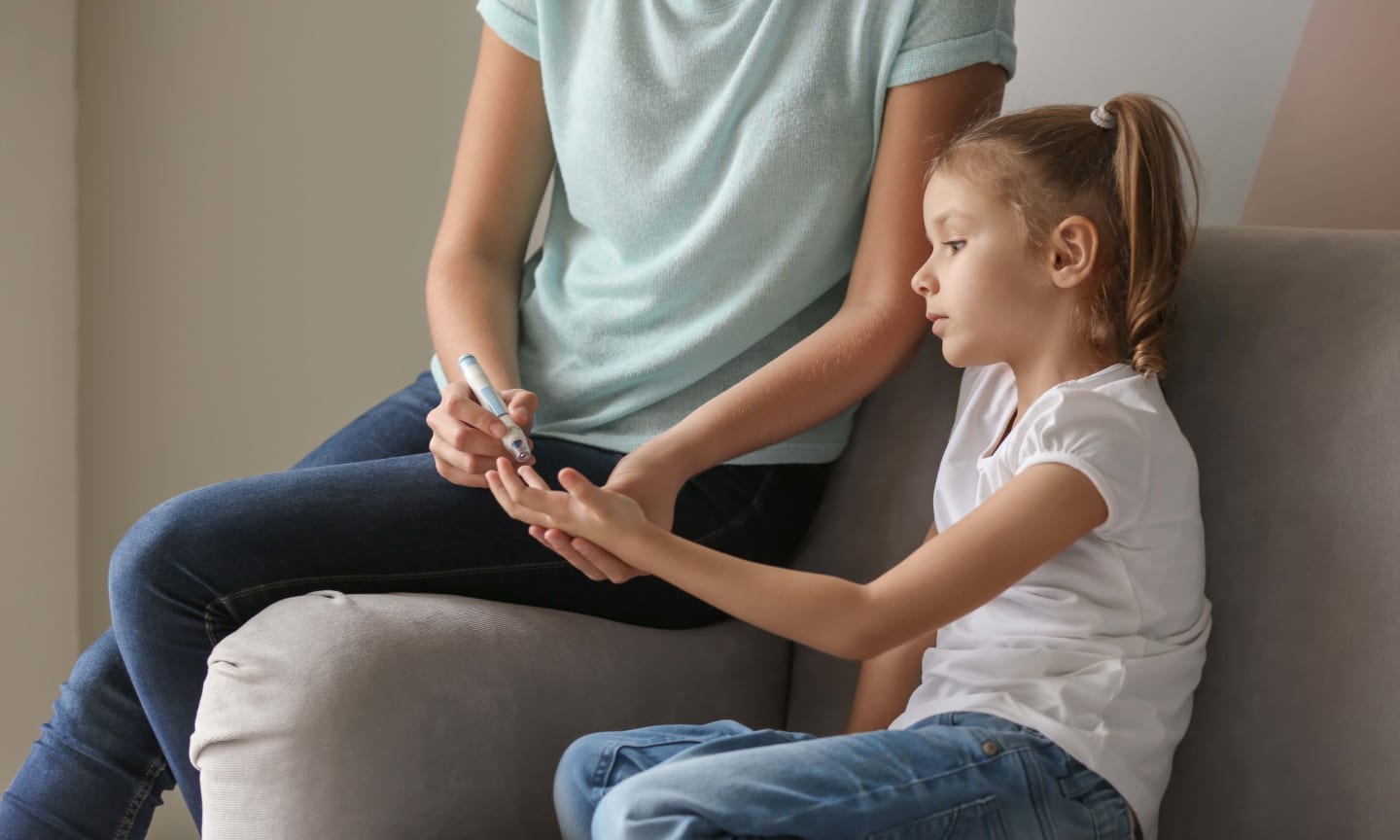 A parent helping their diabetic child take an at-home blood test