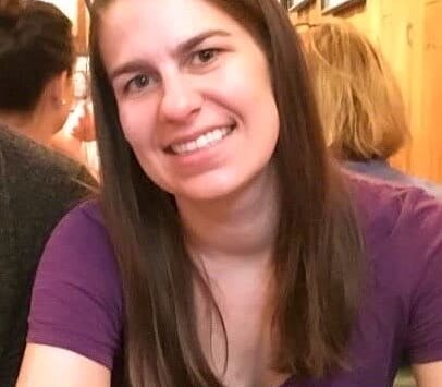 Stephanie Schuldes, as an adult, smiling while leaning on a table