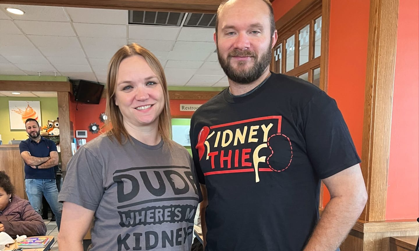 Woman wearing a shirt that says, "Dude, where's my kidney?" standing next to man wearing a shirt that says, "Kidney thief."