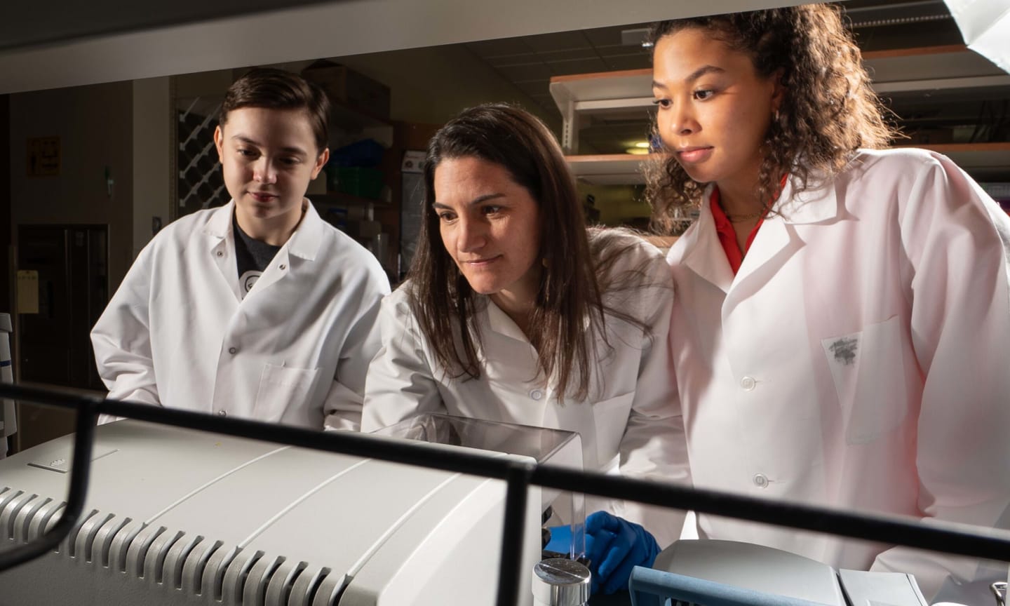 Three scientists working over a lab bench