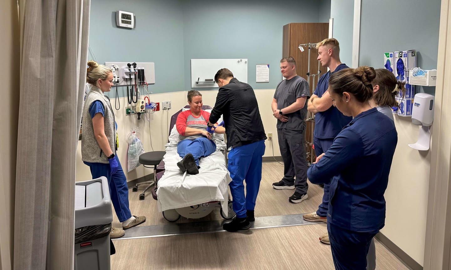 Exam room with medic professionals observing a provider care for a patient during a training session