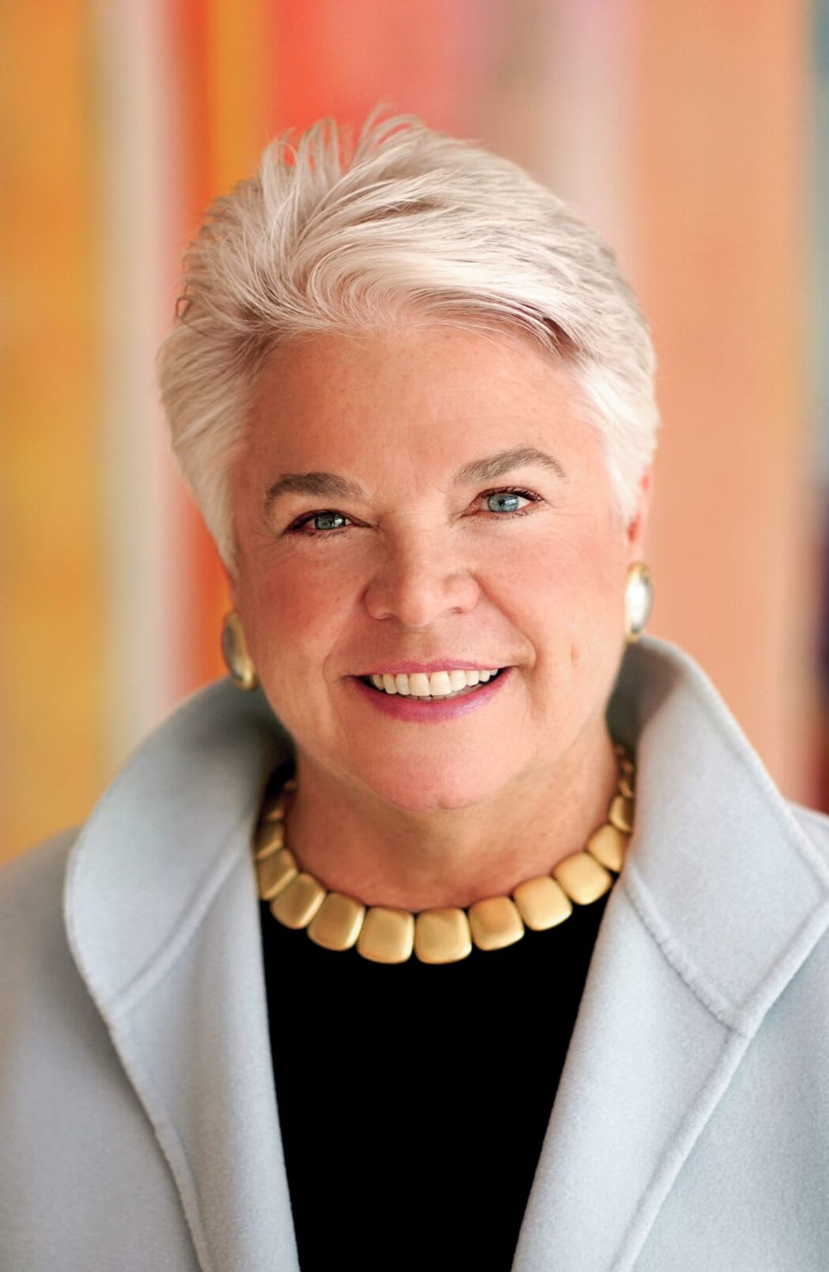 Pleasant Rowland headshot, smiling wearing a grey coat and a necklace.