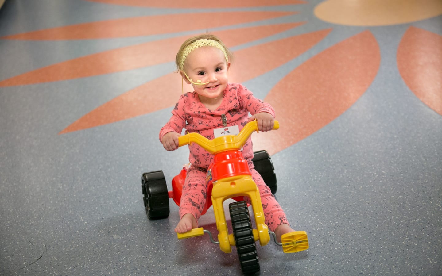 A child riding a tricycle in the hospital while undergoing cancer treatment