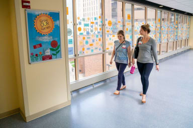 Two UW Health employees walking through a hallway of windows