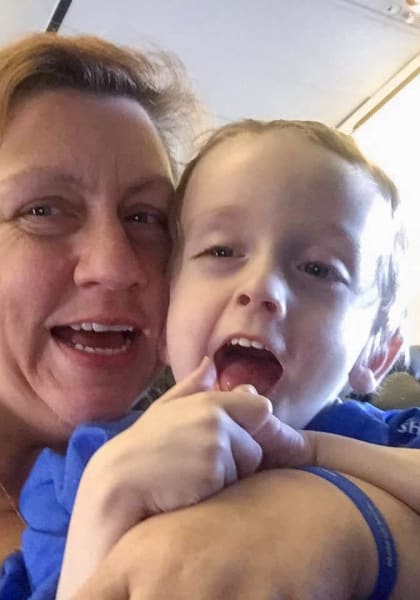 Mary Briggs-Pomo and her son Ben Pomo posing for a selfie on an airplane