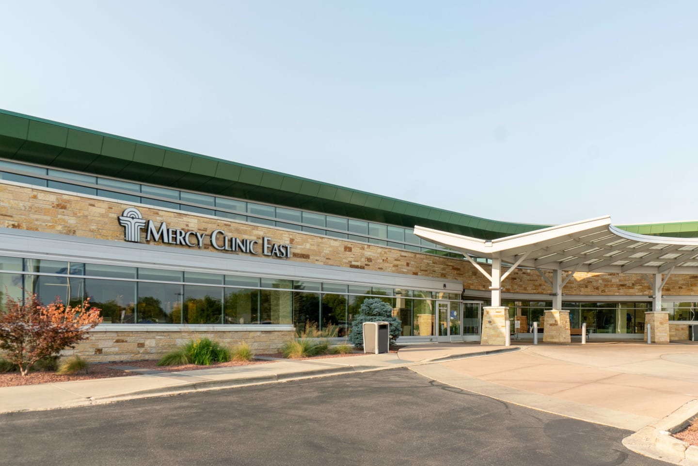 The front entrance of the MercyHealth East Clinic, a cream brick building with a green roof