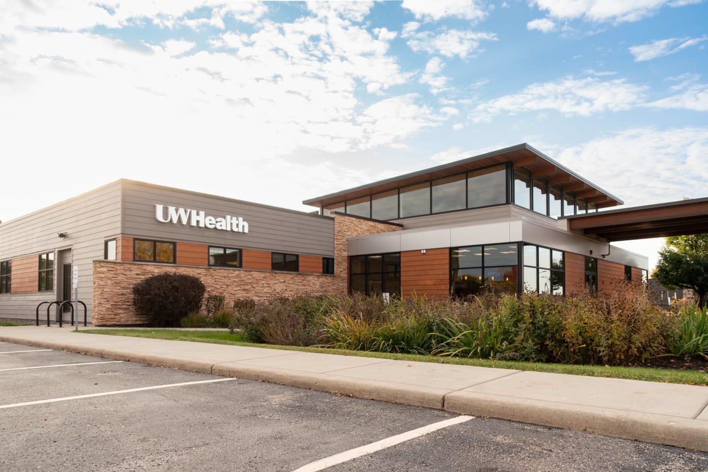 A building with gray siding and red brick with a white UW Health sign